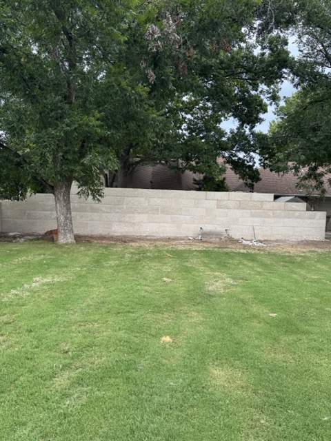 Finished limestone block retaining wall along a mowed yard in San Angelo, TX